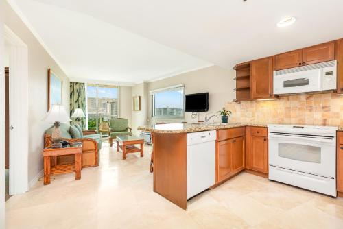 a kitchen with white appliances and a living room at Luana Waikiki Hotel & Suites in Honolulu