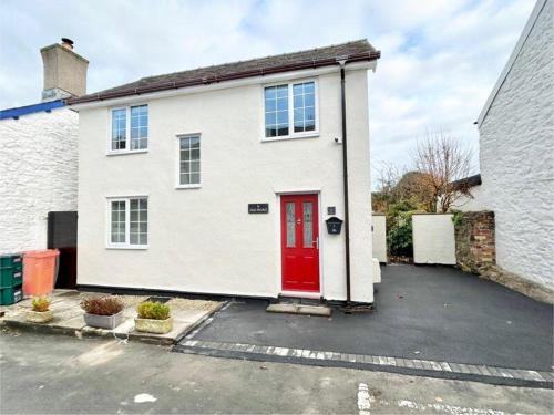 a white house with a red door in a parking lot at Cosy Cottage in Medieval Conwy with garden and parking in Conwy