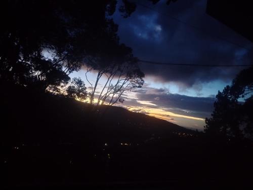 a sunset on a hill with trees in the foreground at Hermosa vista, casa en Boquete. in Boquete