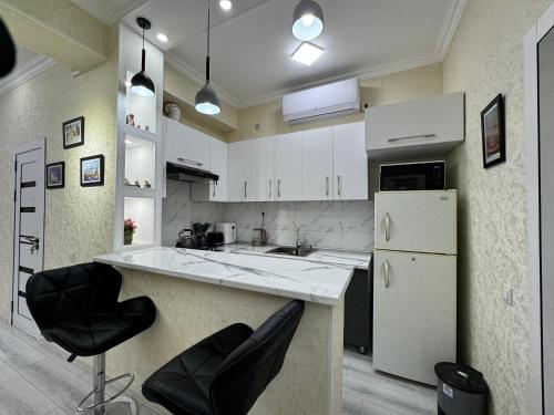 una cucina con armadietti bianchi e sedie nere di Modern 2BR Luxury -10 Min Walk to Old Town a Bukhara