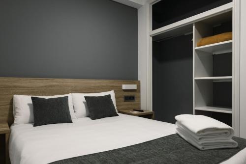 a bedroom with a large white bed and shelves at Hotel Alda Narón in Narón