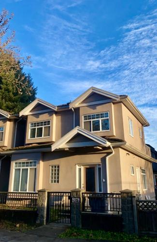 a large house with a fence in front of it at Modern & Cozy 2-Bed Suite in Vancouver in Vancouver