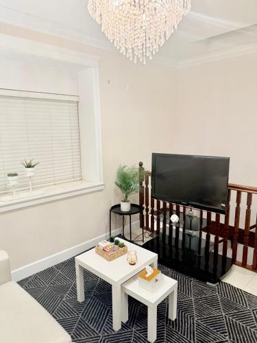a living room with a flat screen tv and a chandelier at Modern & Cozy 2-Bed Suite in Vancouver in Vancouver
