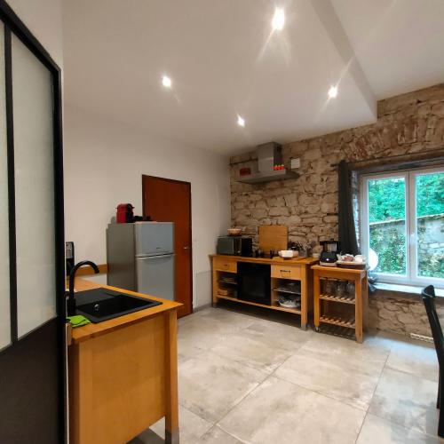 Il comprend une cuisine avec un réfrigérateur et un mur en pierre. dans l'établissement Gites du Longevent Appartement du Moulin Pérouges, à Meximieux