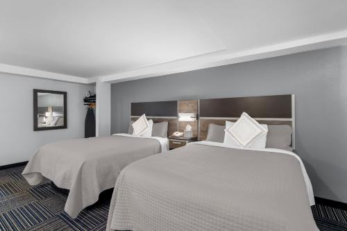 two beds in a hotel room with white sheets at Admiralty Inn & Suites - a Red Collection Hotel in Falmouth