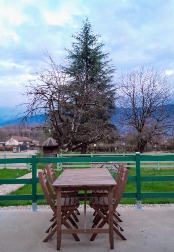 a wooden table and two chairs next to a fence at Le Lodge Morgane Appartement 4 personnes in Barraux