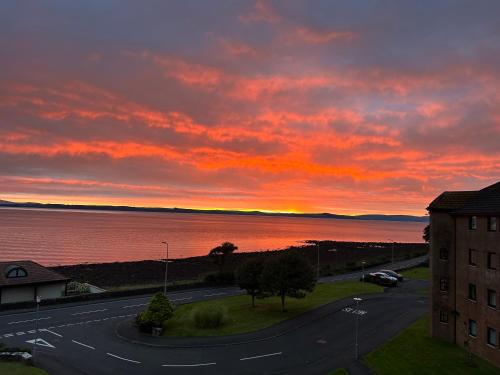 a sunset over the water with a building and a road at View of the Isles in Largs