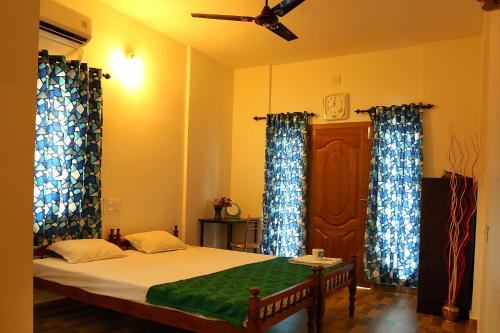 a bedroom with a bed with blue curtains and a ceiling at Heather Home Stay in Cochin