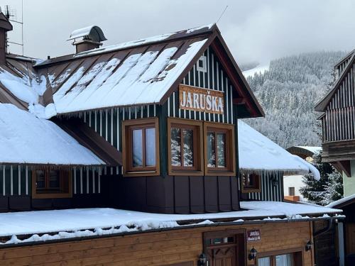 a building with a sign on it in the snow at Pension Jaruska in Špindlerův Mlýn