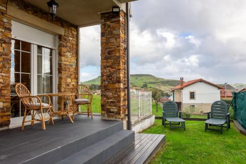 a patio with chairs and a table on a balcony at Los cuetos, casa para 6 personas con jardín y parking, a pocos minutos de Suances in Suances