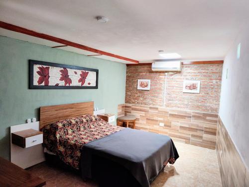 Un dormitorio con una cama y una pared de ladrillo. en Huerta Grande 2, en Huerta Grande