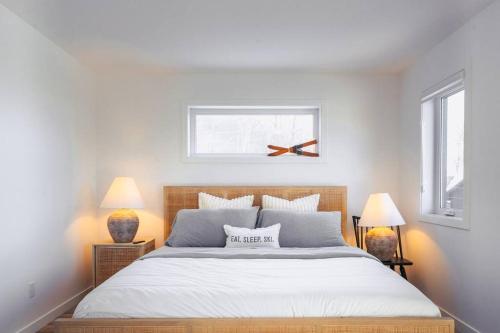 ein Schlafzimmer mit einem großen weißen Bett mit zwei Lampen in der Unterkunft Modern Mont Blanc Ski in Ski out Townhouse in Saint-Faustin