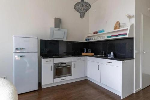a kitchen with white cabinets and a white refrigerator at Boutique Hotel Maldegem in Vlissingen