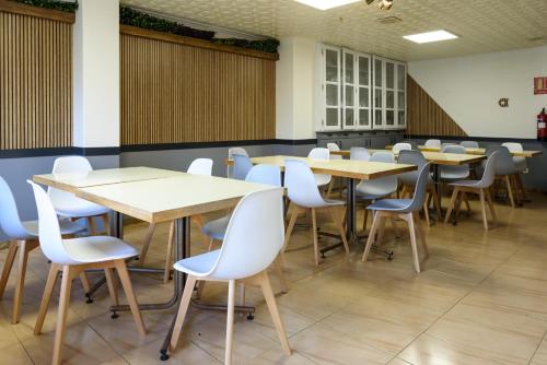 a classroom with wooden tables and white chairs at Hotel Alda Narón in Narón