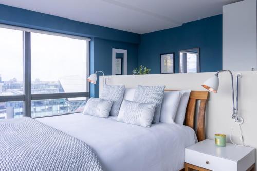 a bedroom with blue walls and a white bed with pillows at GuestReady - Enchanting views from Millenium Tower in Dublin