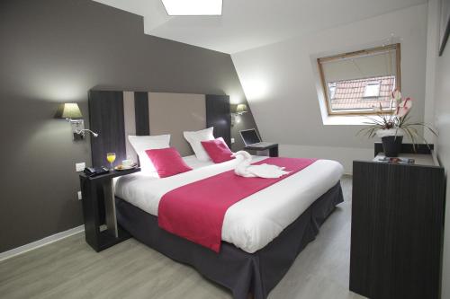 um quarto de hotel com uma cama grande com almofadas vermelhas em Odalys City Strasbourg Green Marsh em Estrasburgo
