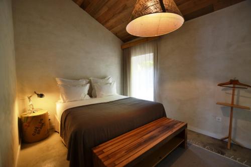 a bedroom with a bed with a bench and a window at Wine Tourism - Quinta do Ameal in Refoios do Lima