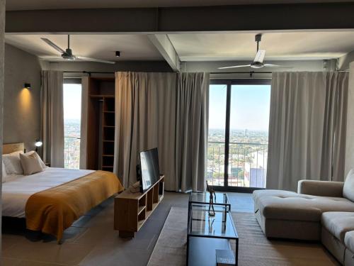 a bedroom with a bed and a tv and a couch at Departamentos y Suites Índigo in Querétaro