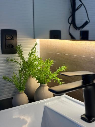 two white vases with plants in them on a counter at Flat Vista Mar Praia Long Stay in Vitória