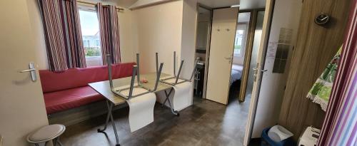 une chambre avec une table en verre et un canapé rouge dans l'établissement jurfftyg, à Biville-sur-Mer