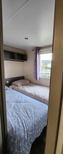 deux lits dans une petite pièce avec une fenêtre dans l'établissement jurfftyg, à Biville-sur-Mer