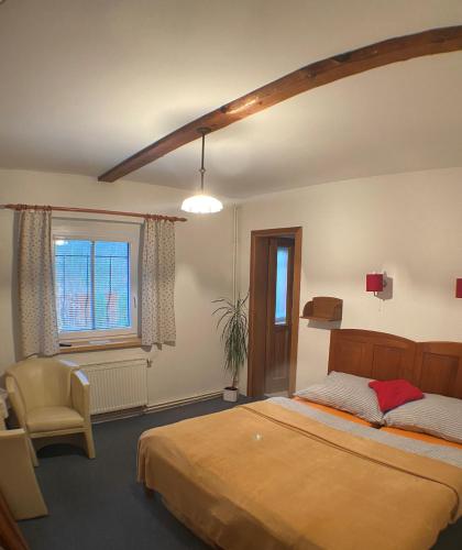 a bedroom with a bed and a chair and a window at Chata Paperule in Horní Maršov