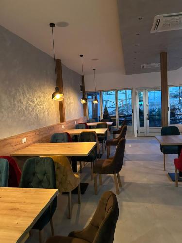 Un restaurante con mesas y sillas de madera y ventanas. en Kraljev Konak, en Kopaonik