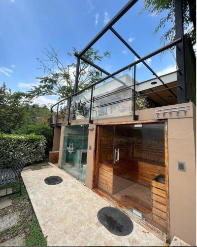 a glass house with a balcony and a patio at Hotel Casa Ambrosia in Villeta