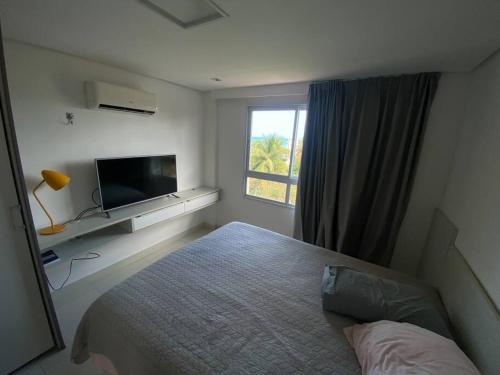 une chambre avec un lit, une télévision et une fenêtre dans l'établissement Cobertura 3 suítes com 1 dependência, à Pirangi do Norte