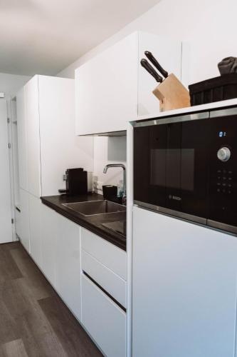a white kitchen with a sink and a microwave at Lebe`schlitters - Das Ferienapartmenthaus im Zillertal in Schlitters