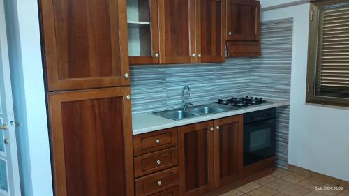 a kitchen with wooden cabinets and a sink at Appartamenti Manuela in Cala Gonone