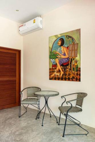 two chairs and a table in a room with a painting at Art Luxe Homes Chiang Mai in Doi Saket