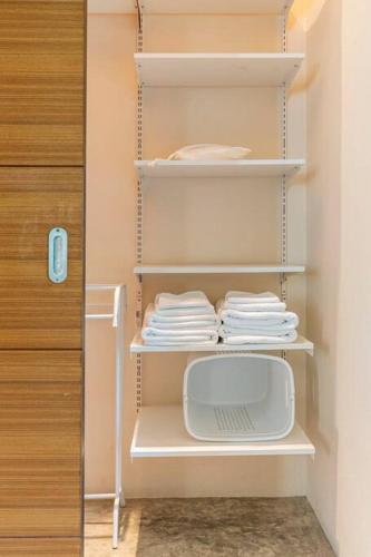 a closet with white shelves with towels and a door at Art Luxe Homes Chiang Mai in Doi Saket