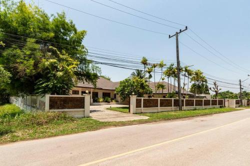 an empty street with a fence in front of a house at Art Luxe Homes Chiang Mai in Doi Saket
