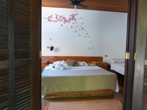 a bedroom with a bed with flowers on the wall at Suítes o Flautista in Ubatuba