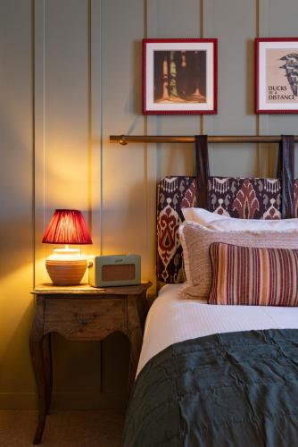 a bedroom with a bed and a table with a lamp at The Royal Forest - A Heartwood Inn in Chingford