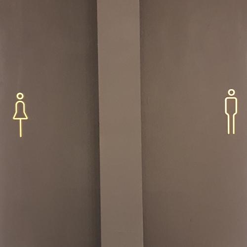 a bathroom stall with a man and a toilet sign at SAM - your cozy stay near Hamburg-Airport in Hamburg