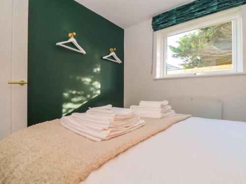 a bedroom with a white bed with a window and hangers at Fifty Degrees North in Penzance