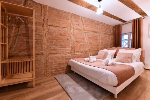 une chambre avec un grand lit avec un mur de briques dans l'établissement La vie en rose - 6P-3BR, à Colmar