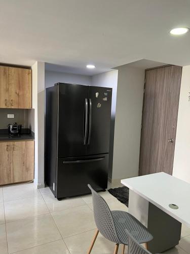 a black refrigerator in a kitchen with a table and chairs at Private Room Sabaneta in Sabaneta