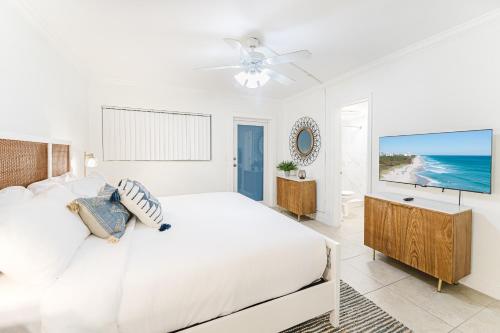 a white bedroom with a bed and a flat screen tv at Elegant Escape! in Boca Raton