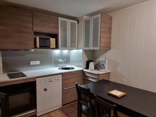 une cuisine avec des placards en bois et une table noire avec une table dans l'établissement Signal du Prorel Briançon Serre Chevalier 