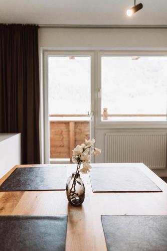 a vase with flowers sitting on a wooden table at Lebe`schlitters - Das Ferienapartmenthaus im Zillertal in Schlitters