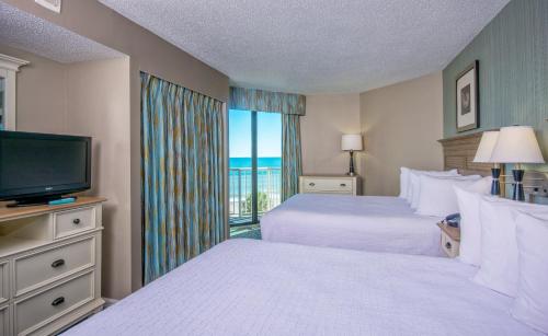 a hotel room with two beds and a flat screen tv at The Strand - A Boutique Resort in Myrtle Beach