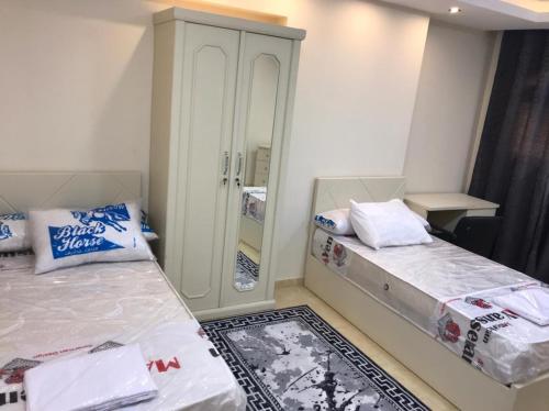two beds in a small room with a mirror at فندق رويال هوم in Mansoura