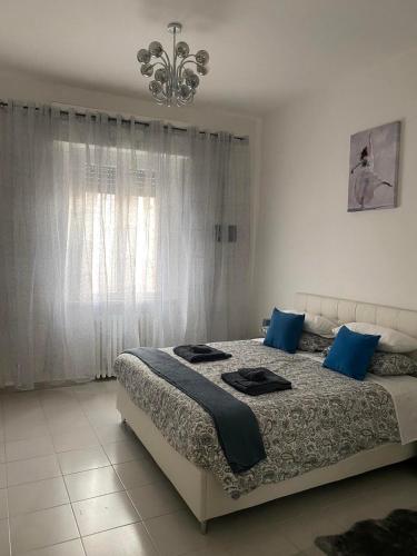 a bedroom with a bed with blue pillows and a chandelier at Casa ELLI in Rimini