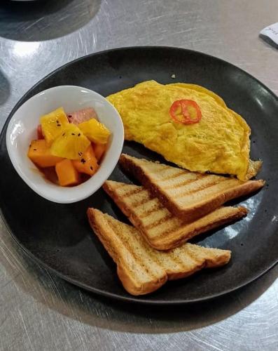 a plate with an egg and toast and a bowl of fruit at Riosol Hotel Tarapoto in Tarapoto