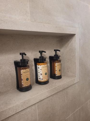 three bottles of soap sitting on a shelf in a bathroom at CHALÉ NAMATA 201 in São Roque