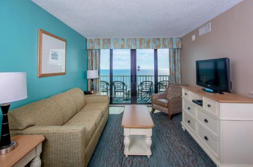 a living room with a couch and a flat screen tv at The Strand - A Boutique Resort in Myrtle Beach