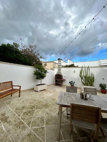 a patio with benches and a fireplace on a white wall at La Maison de Nicole 2 in Carmiano